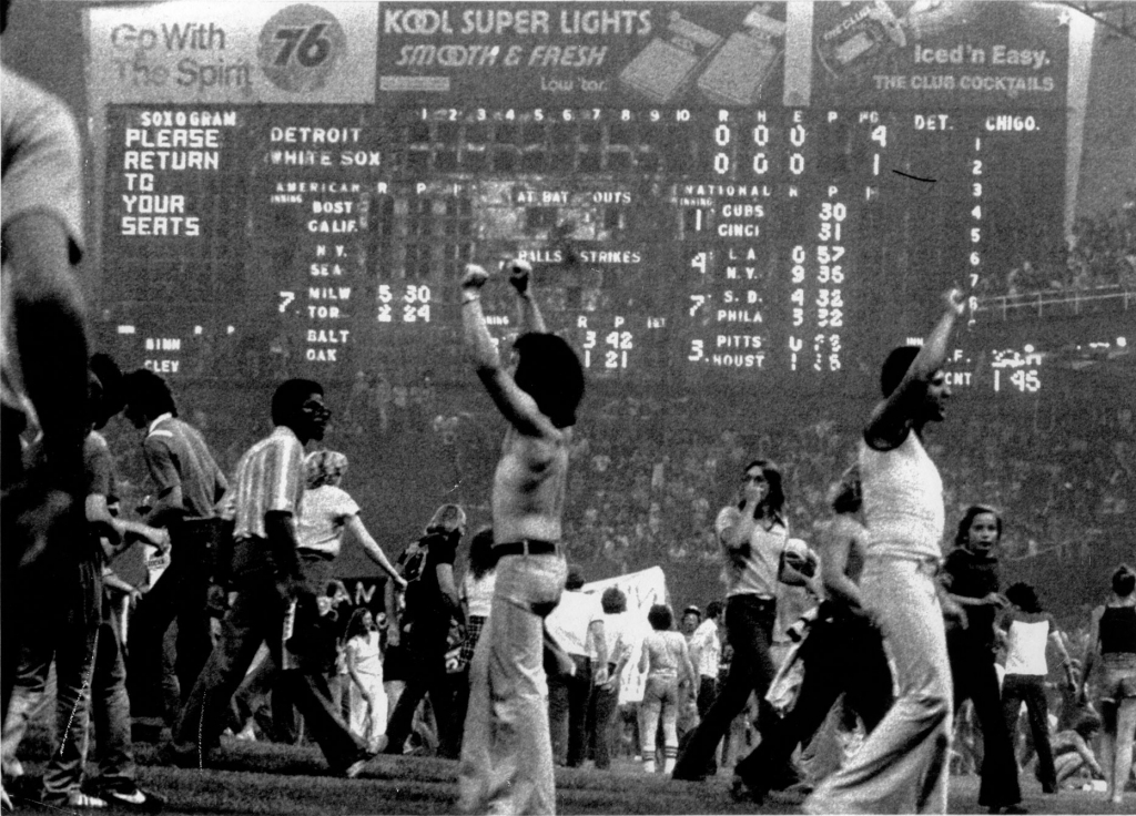 7/13/1979 -- The White Sox scoreboard message goes unheeded as thousands of spectators engulf the field during an anti-disco demonstration that caused the second game of a double-header to be called off. Detroit won the opener 4-1. UPI photo by Hank DeGeorge.(demolition,Comiskey park,baseball pro,Chicago)